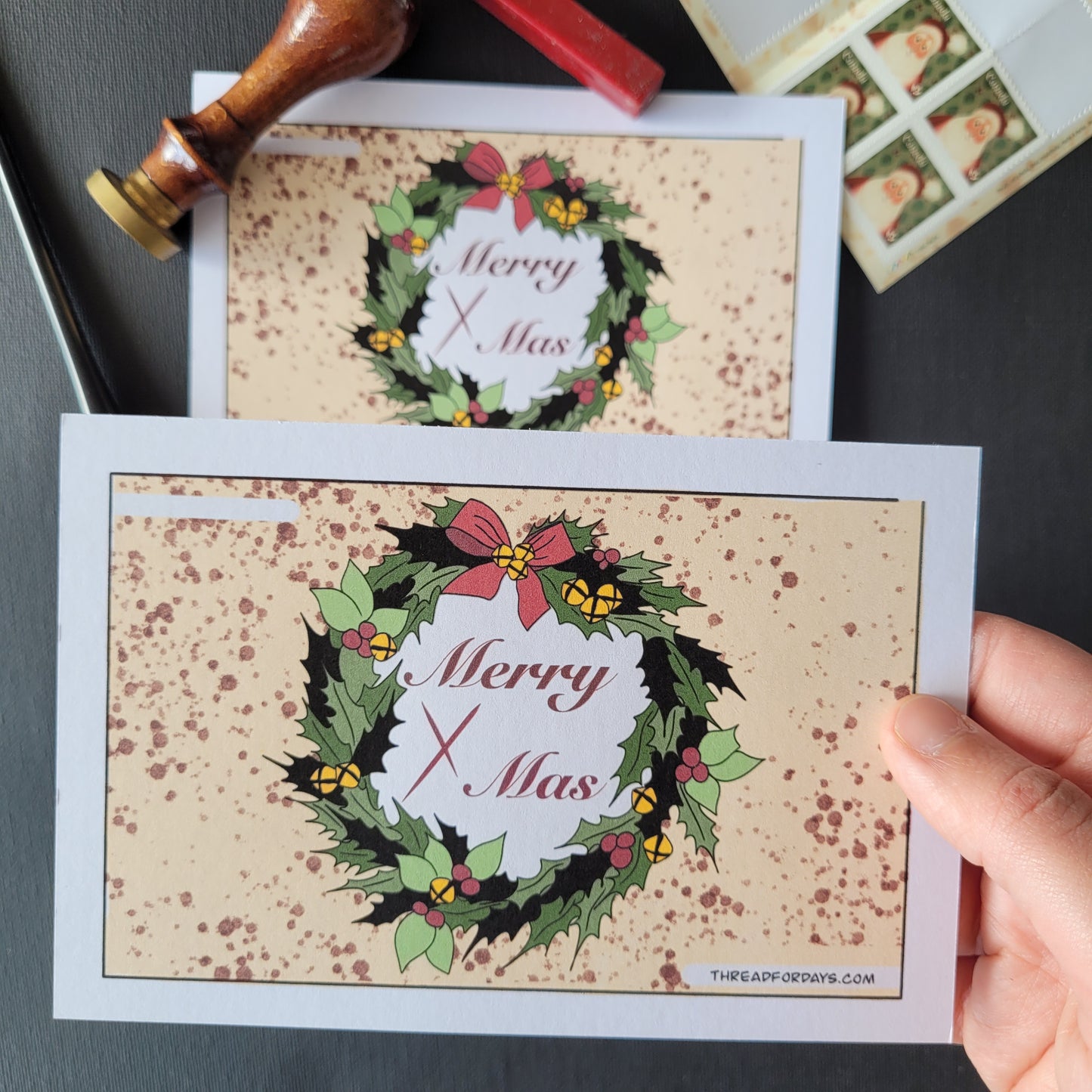 front of the black christmas postcard. Features the black christmas wreath with text "merry Xmas" in the centre. Blood spatter is all around the wreath
