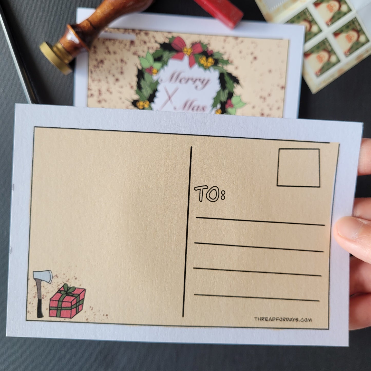 back of the Black christmas postcard. features a small present and a hatchet on the back corner of the card