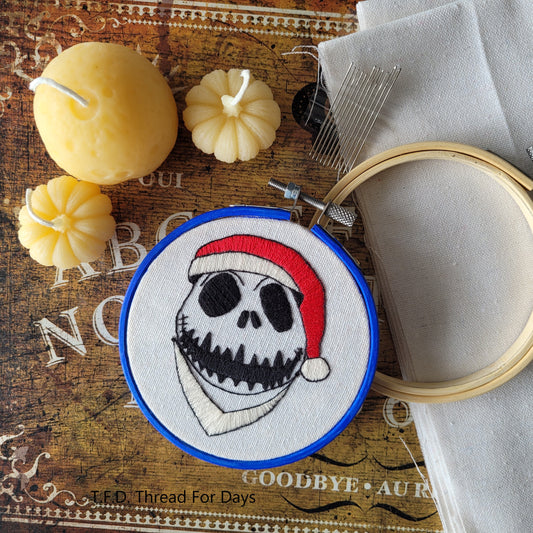jack skellington embroidery hoop resting on fabric, 4inch bamboo hoop, and embroidery needles