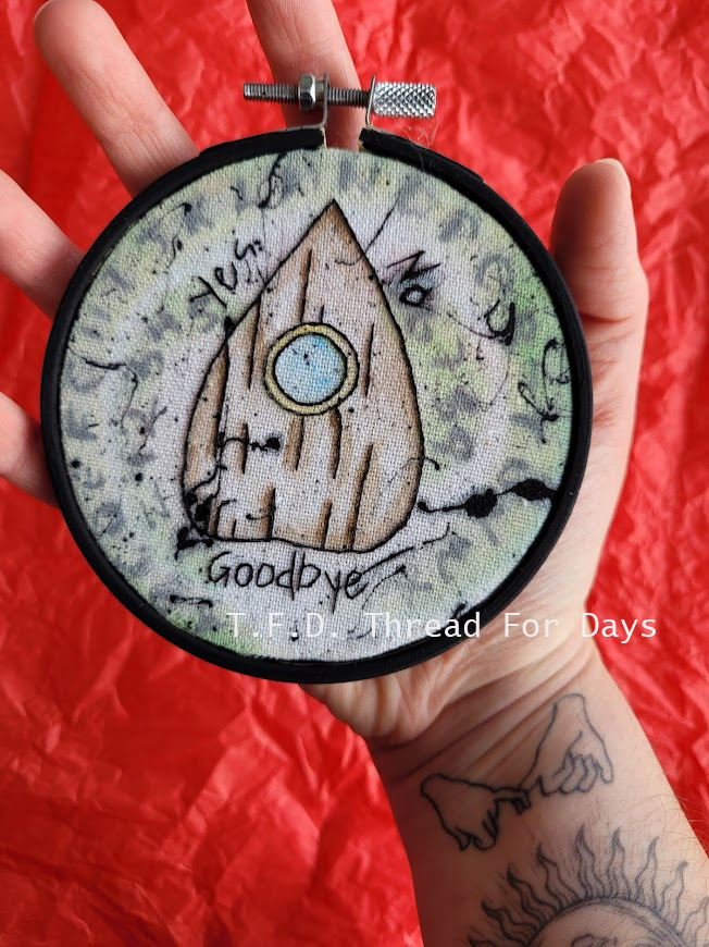 ouija planchette embroidery hoop held in palm of hand