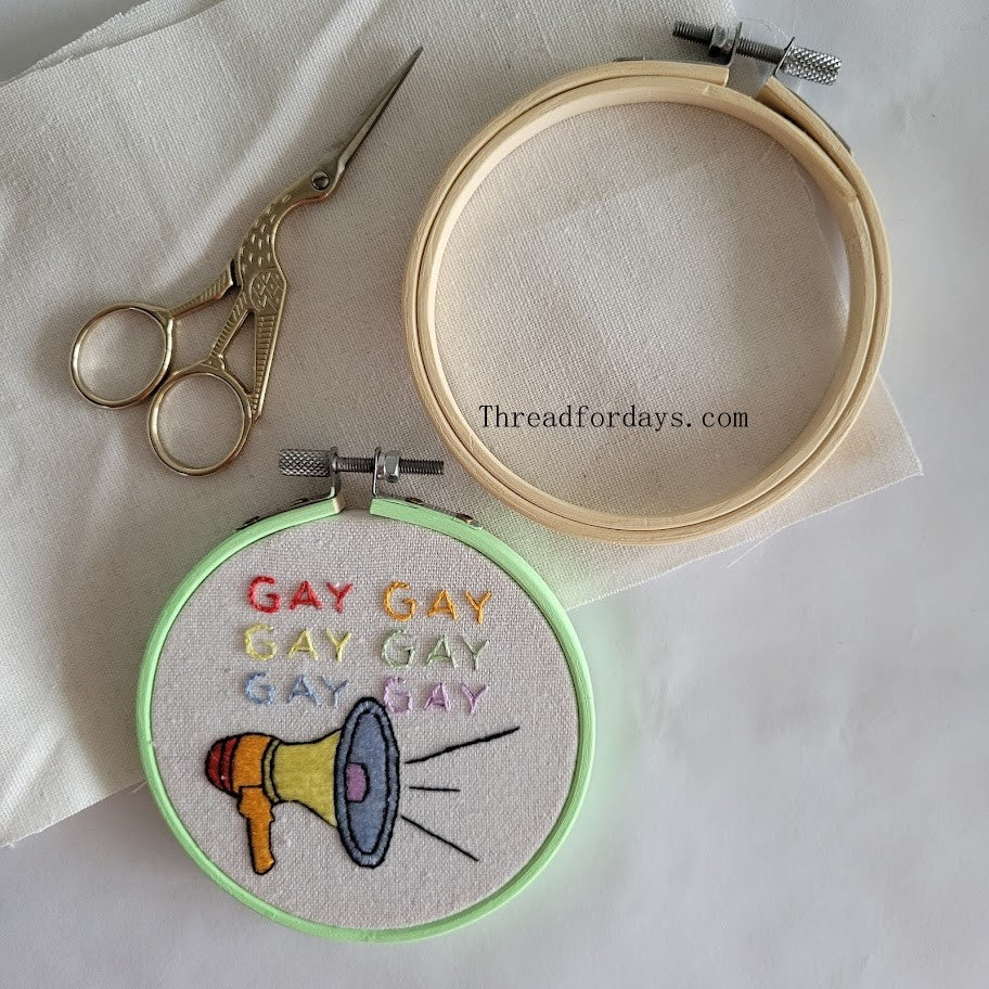 say gay hoop on aida cloth. 4inch embroideyr hoop and scissors in the photo