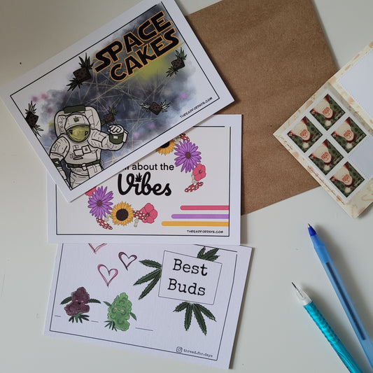 space cakes, vibes, and best buds postcards displayed on a table.