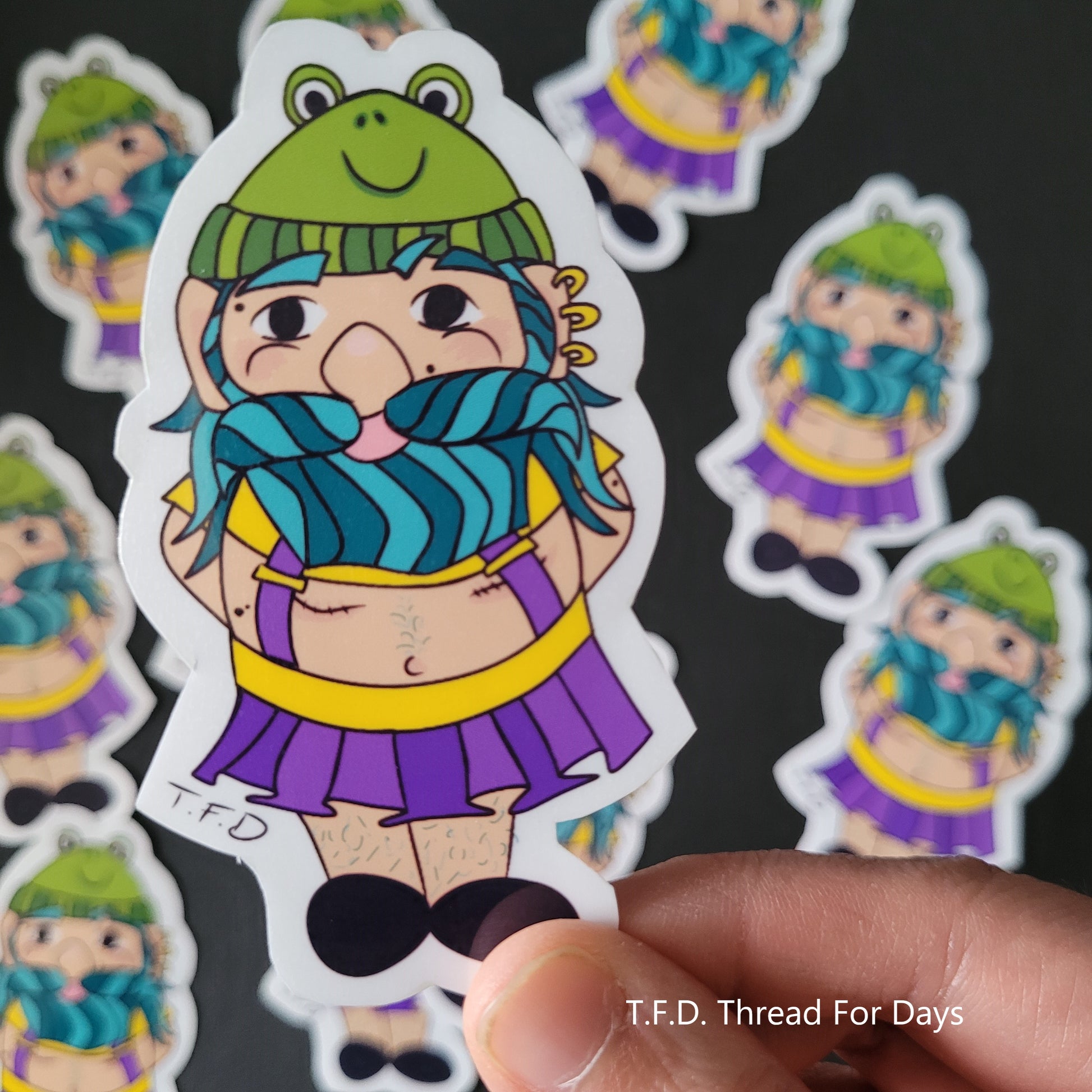 non-binary gnome sticker held between fingers
