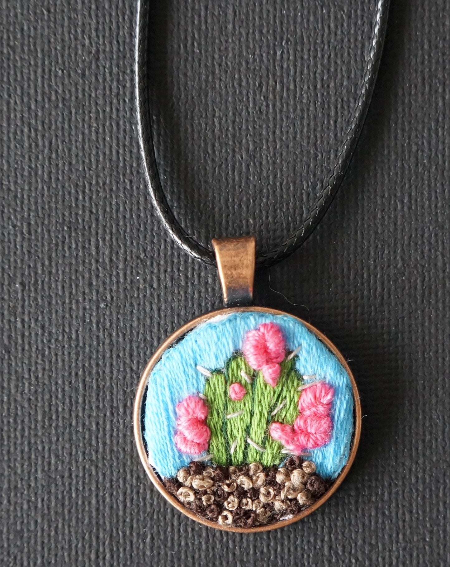 cacstus embroidered pendant with french knot textured "dirt" and french knot pink flowers