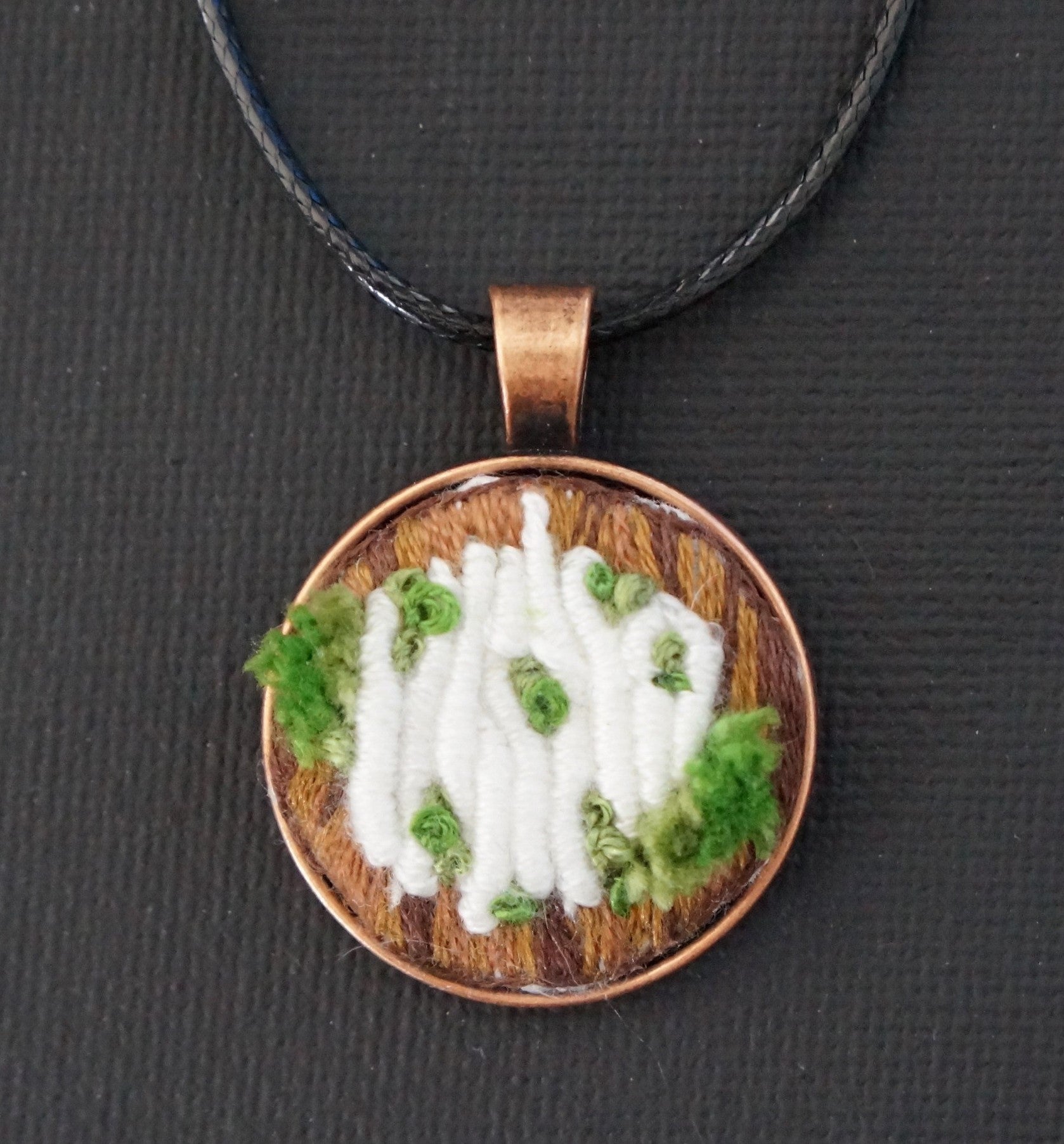 embroidered pendant of white bullion knot fungus on a tree trunk with green french knot moss